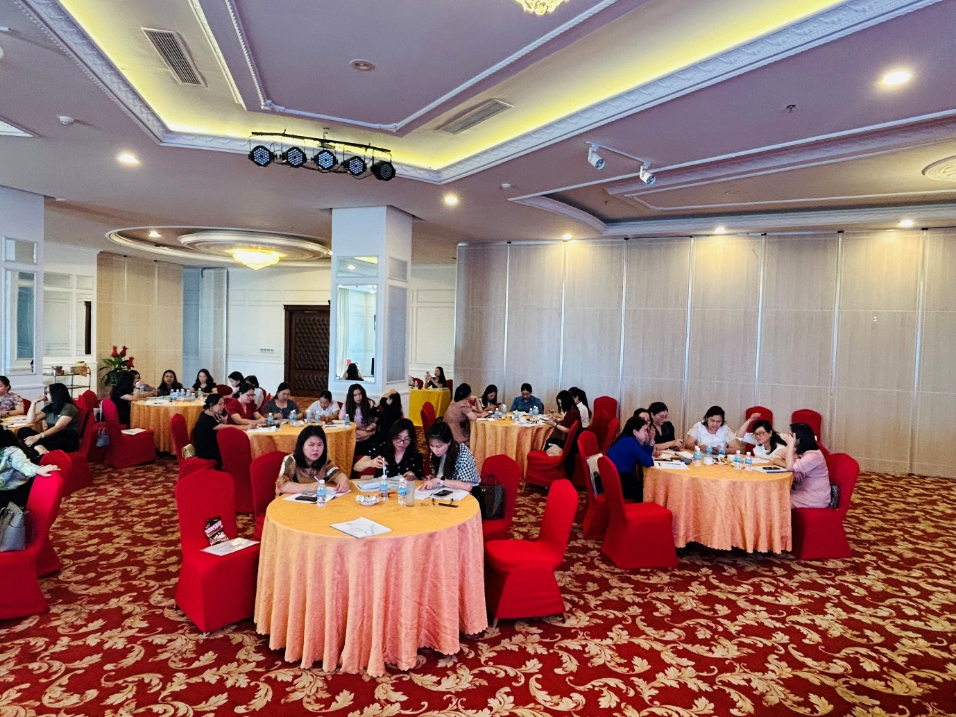 A group of people sitting at tables in a room Description automatically generated